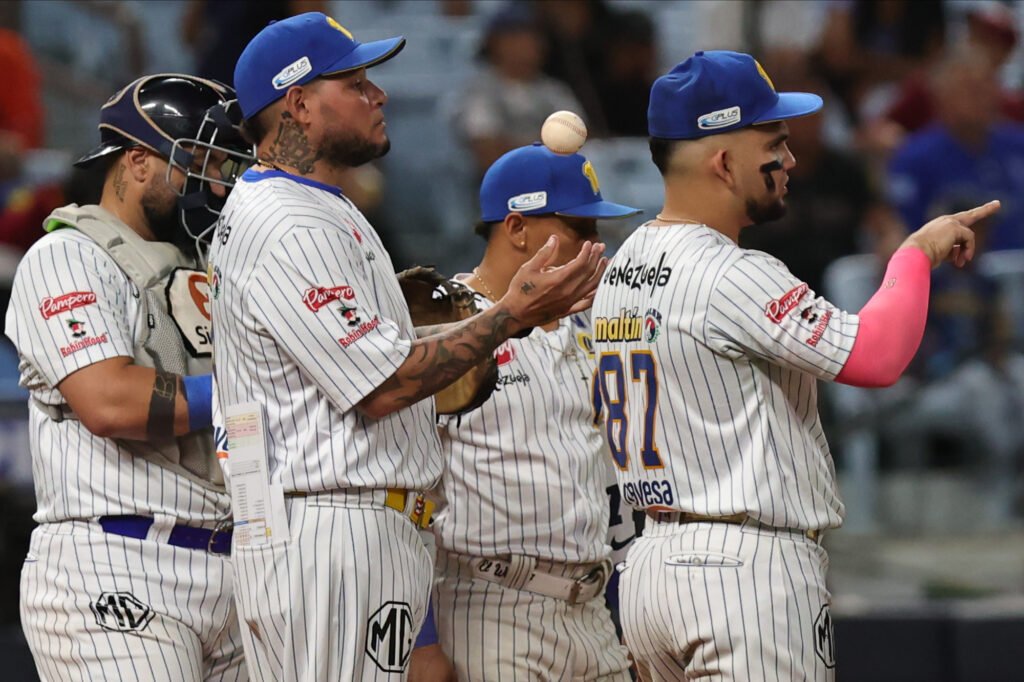 Jugadores de Navegantes del Magallanes reunidos en el montículo con la pelota en el aire durante un juego de la LVBP