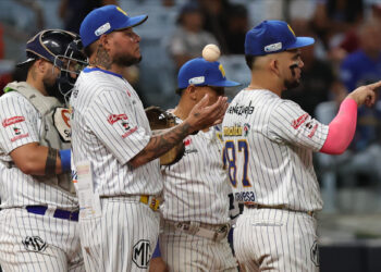Jugadores de Navegantes del Magallanes reunidos en el montículo con la pelota en el aire durante un juego de la LVBP