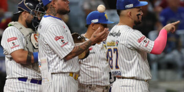 Jugadores de Navegantes del Magallanes reunidos en el montículo con la pelota en el aire durante un juego de la LVBP