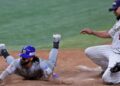Miguel Aparicio de los Navegantes del Magallanes se desliza de cabeza en el plato mientras el lanzador de los Leones del Caracas, Mayckol Guaipe cubre la goma