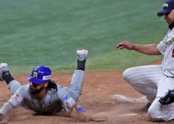 Miguel Aparicio de los Navegantes del Magallanes se desliza de cabeza en el plato mientras el lanzador de los Leones del Caracas, Mayckol Guaipe cubre la goma