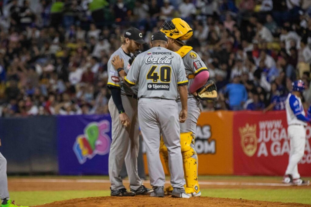 Lanzador, receptor y cuerpo técnico en una visita al montículo del pitcheo de los Leones del Caracas